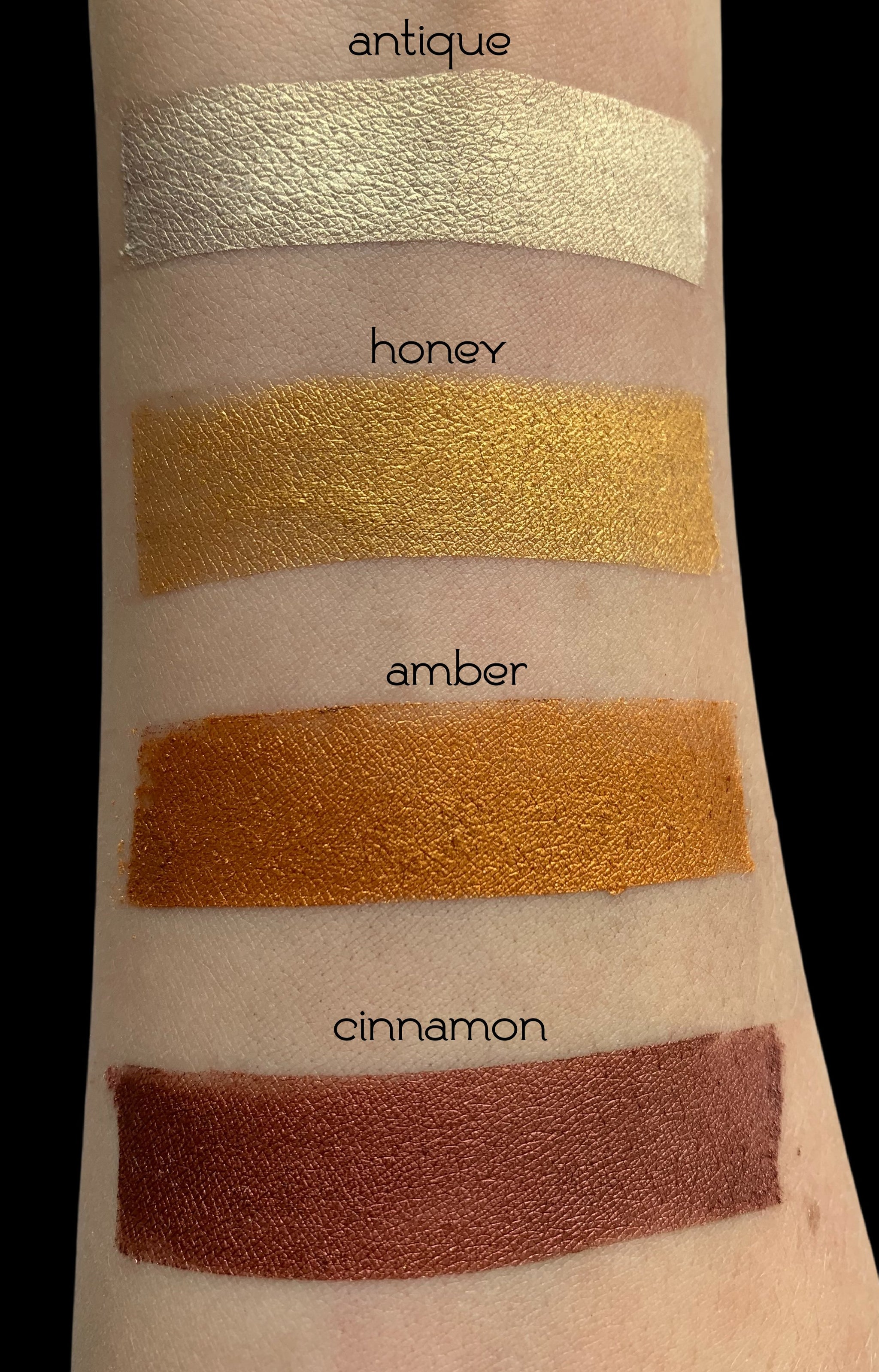 arm showing color swatches of loose eyeshadow in shades of browns - antique, honey, amber and cinnamon.